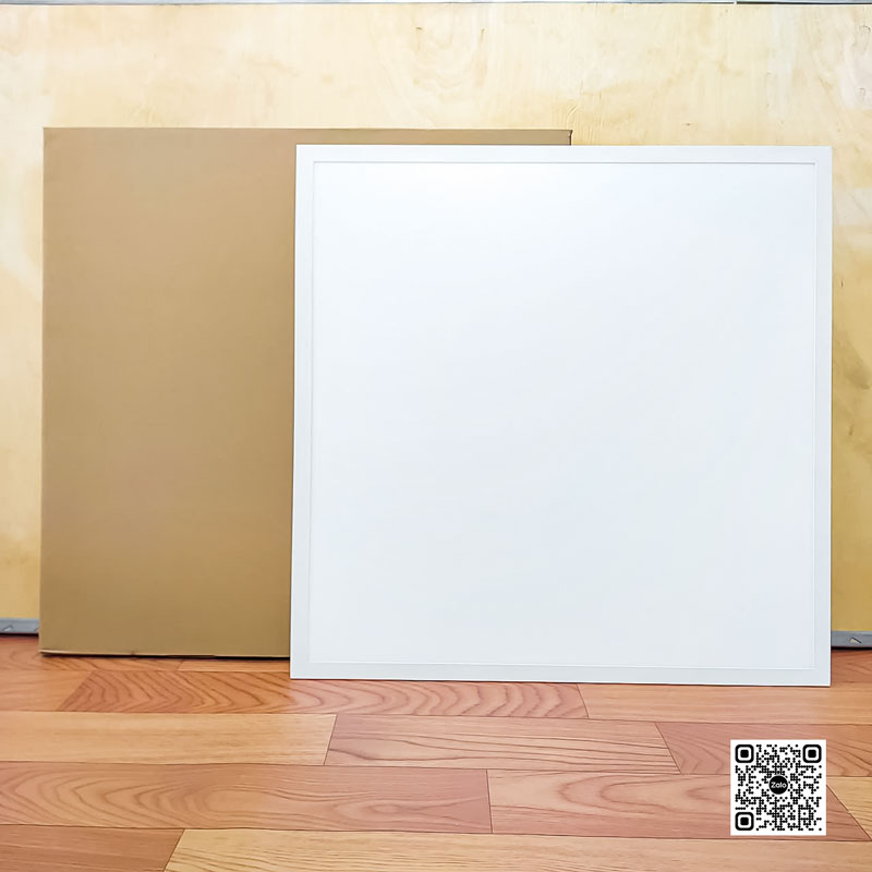 Tấm panel trần vuông màu trắng đặt trên sàn gỗ cạnh hộp carton nâu